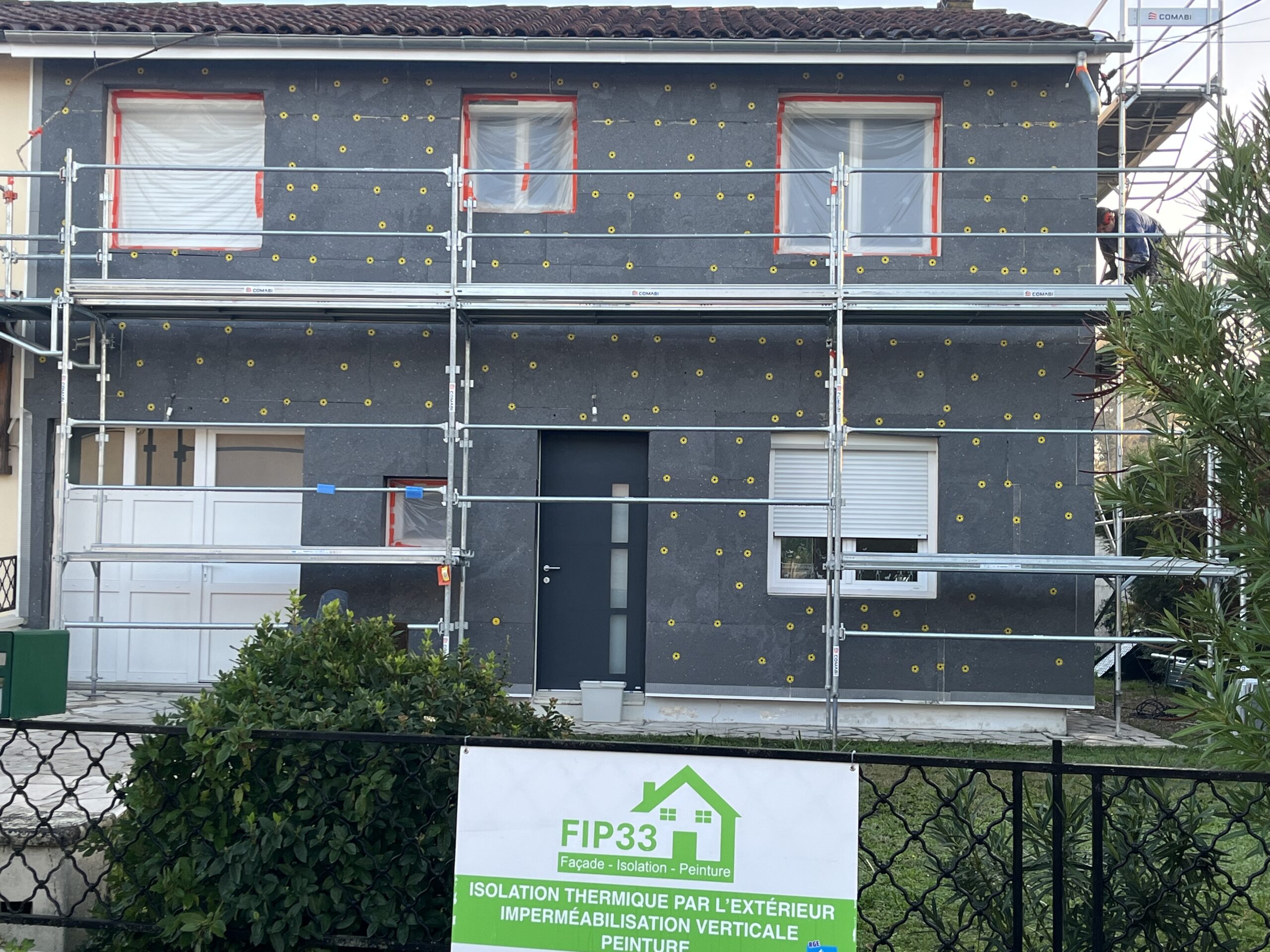 Artisan posant des panneaux isolants en façade dans le cadre d’une isolation thermique par l’extérieur pour améliorer la performance énergétique d’une maison.